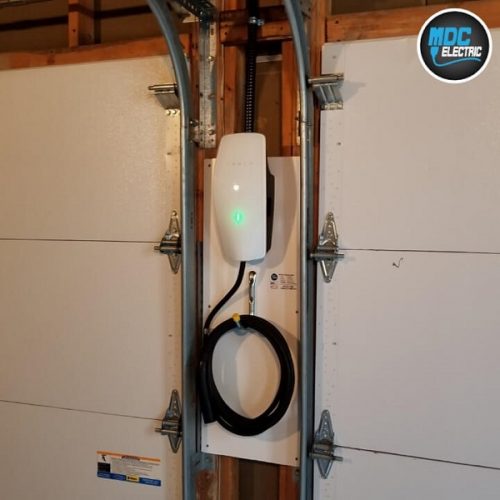 Tesla gen 3 wall connector installed between garage doors by MDC Electric