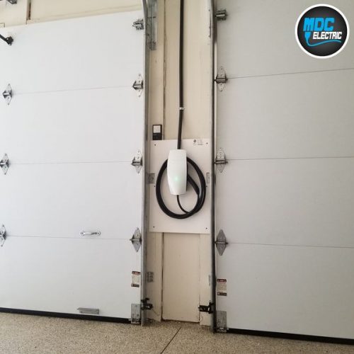 Tesla EV charger between garage doors by MDC Electric